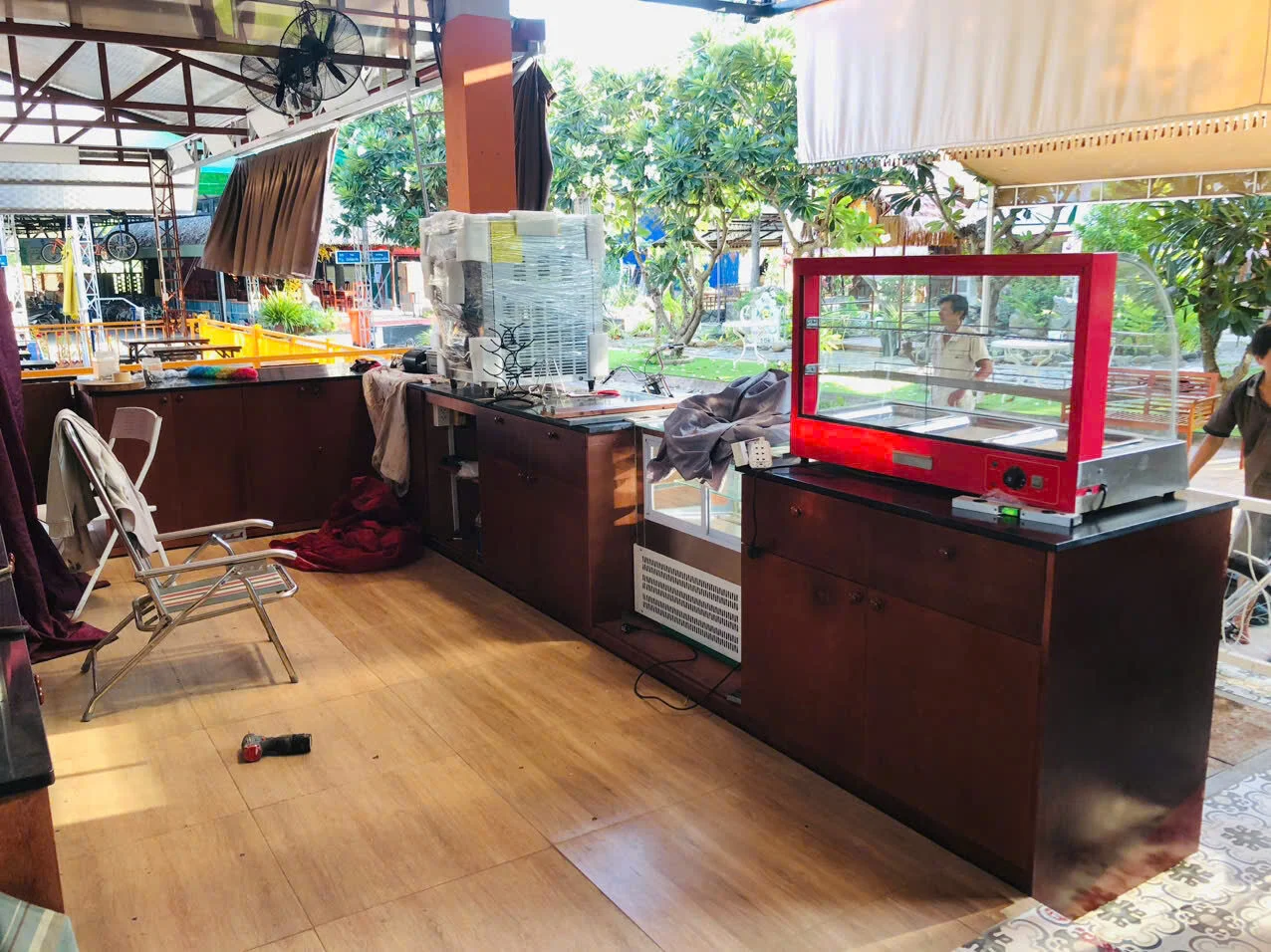 Tủ kính khung đỏ và thiết bị đặt trên hệ tủ thấp trong khu phục vụ đang thi công