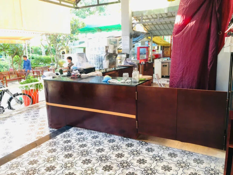 Mặt ngoài quầy phục vụ tông nâu đỏ nhìn từ lối đi bên hông tại công trình Bluecons