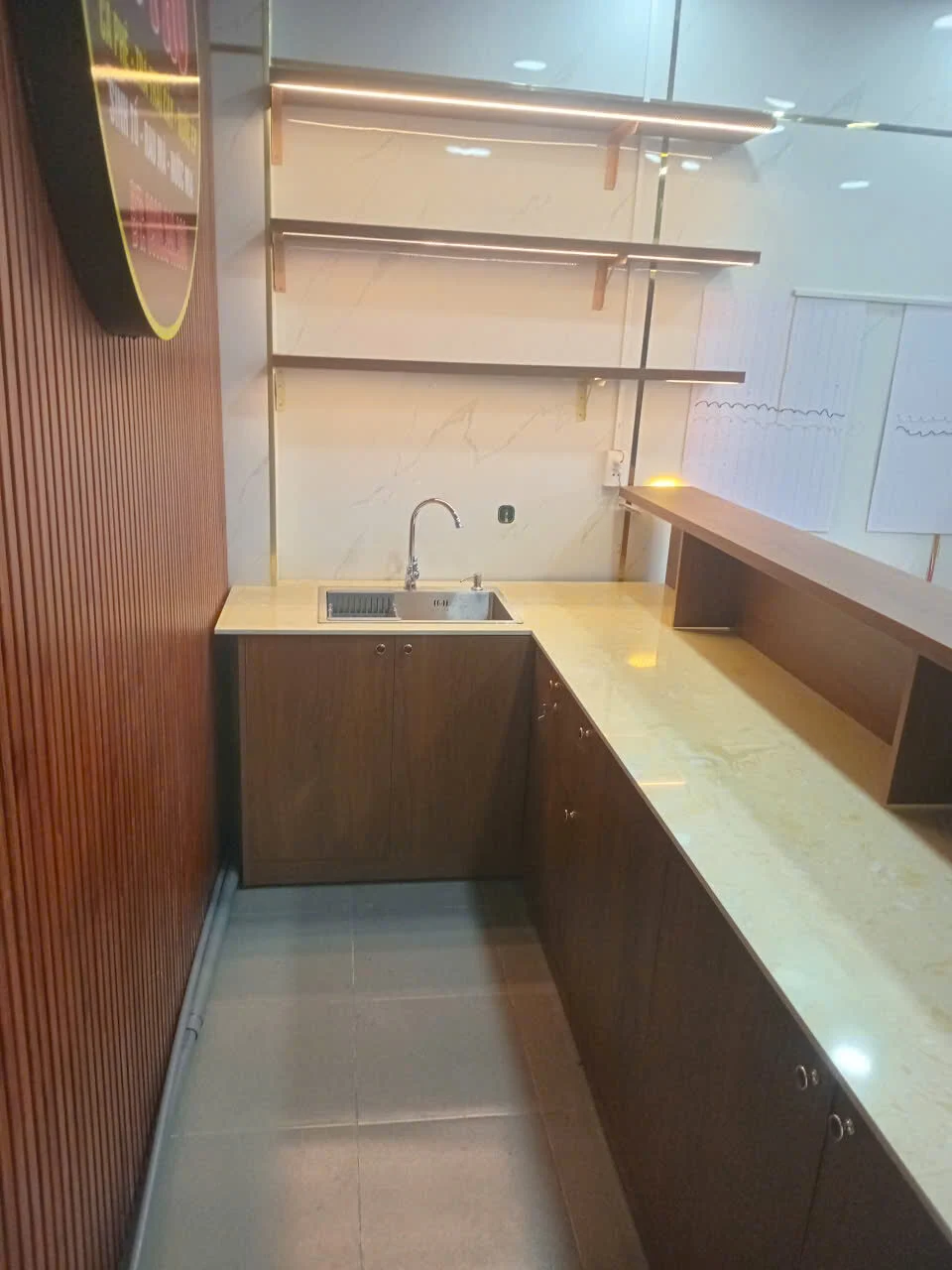Phía sau quầy MDF có mặt bàn dài bồn rửa tủ dưới và kệ treo tại Quận 7