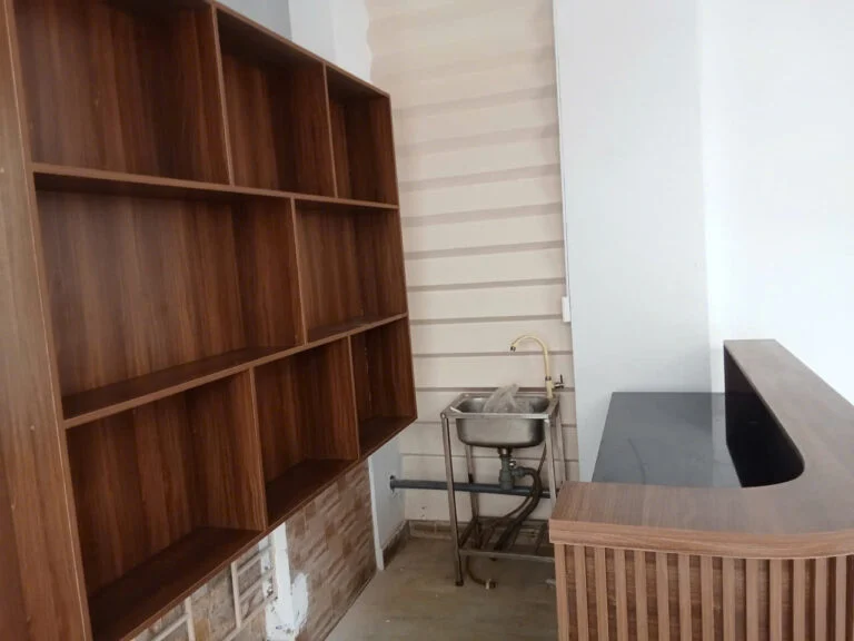 Hệ kệ và quầy MDF vân gỗ đang lắp đặt cạnh bồn rửa tại Quận 7