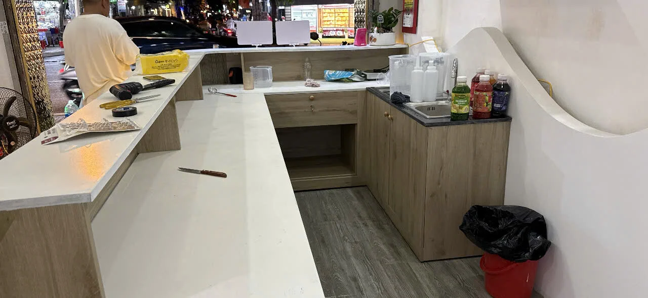 Bên trong quầy gỗ MDF chữ U có mặt bàn sáng màu và khoang tủ tại Quận 7