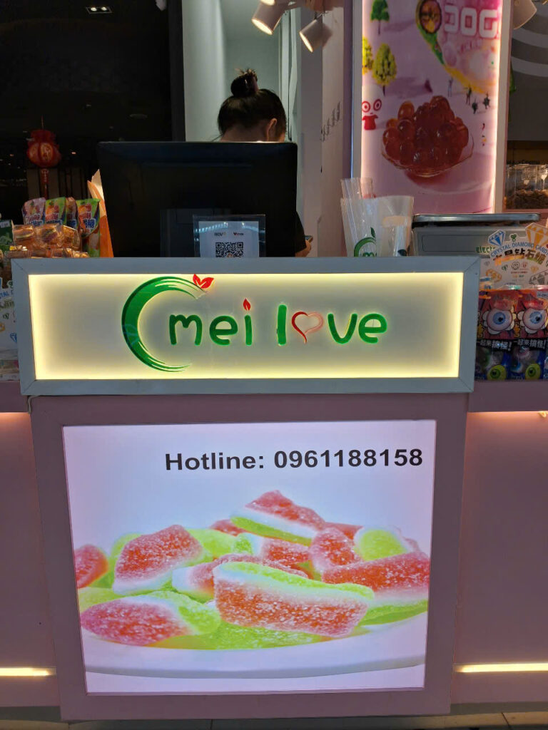 Logo MELOVE có đèn nền tại quầy thu ngân bánh kẹo trong khu thương mại