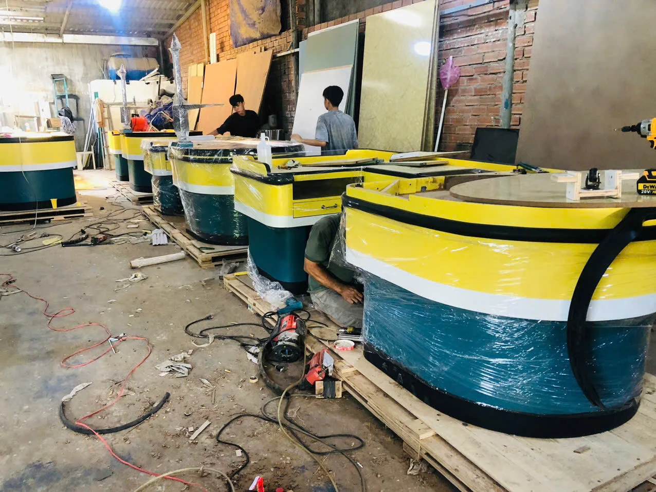 Nhiều quầy cong màu vàng xanh trắng đang gia công và bọc bảo vệ tại xưởng Bluecons